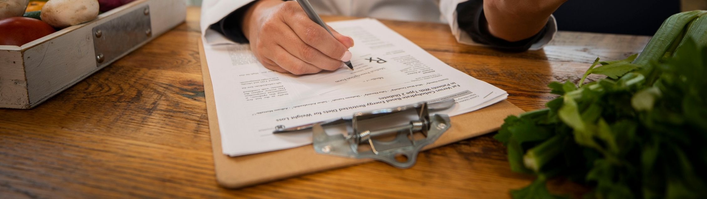 Hands writing nutrition prescription on clipboard