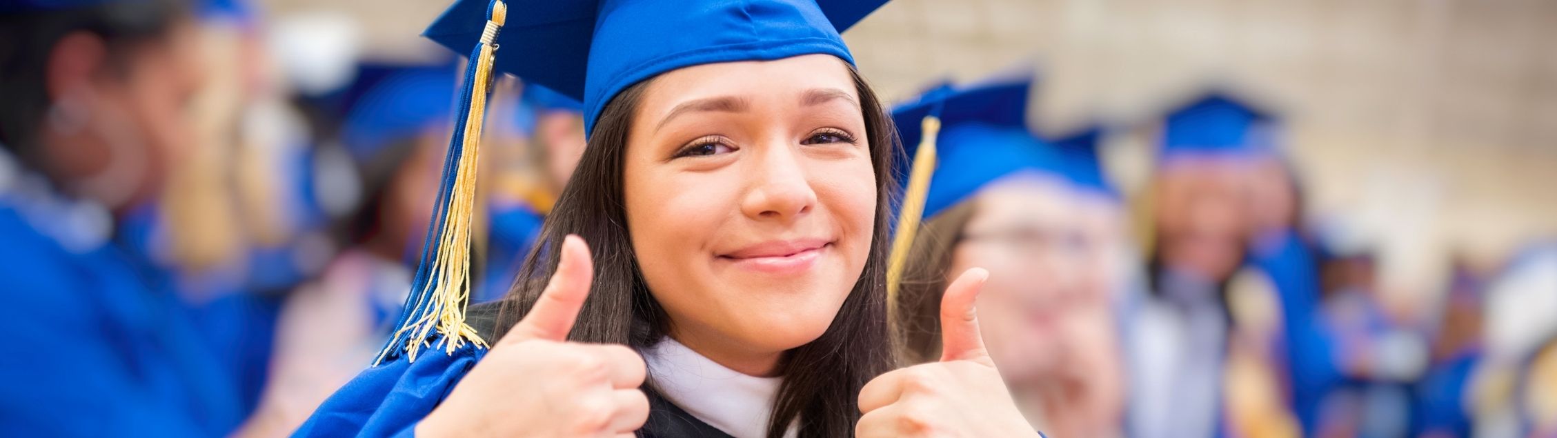 Girl in graduation gown giving two thumbs up