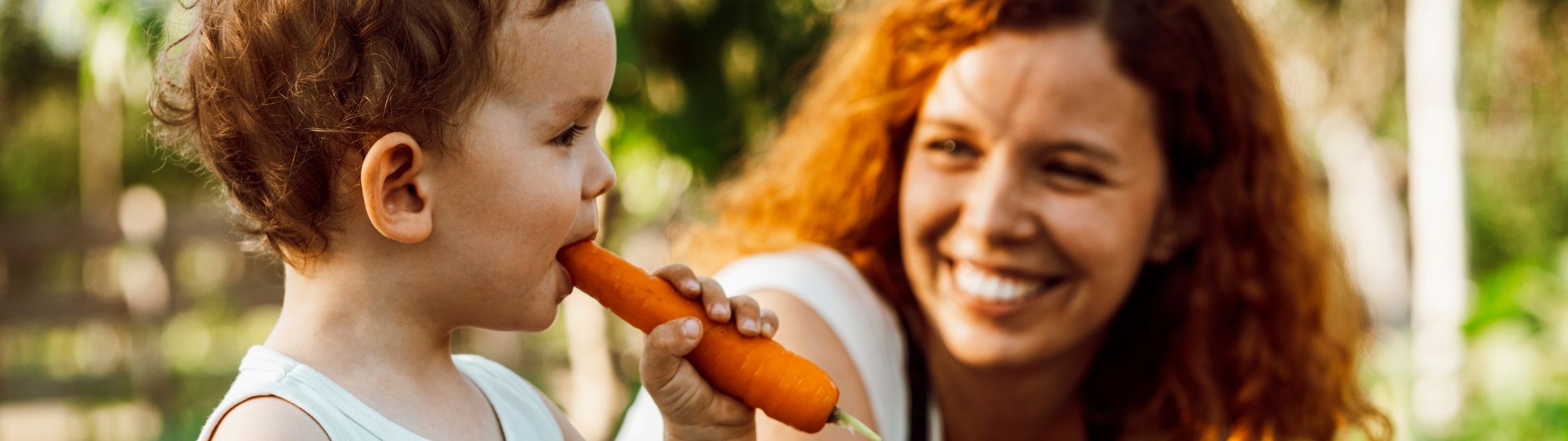 Toddler eating a fresh carrot