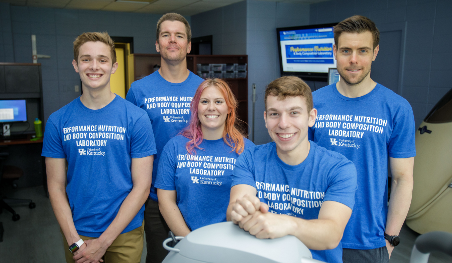 Students in blue shirts pose in the lab